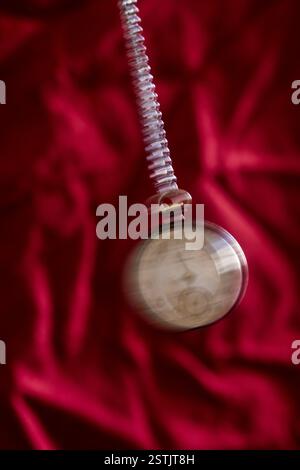 Vintage Taschenuhr schwingt über einem roten Hintergrund. Stockfoto