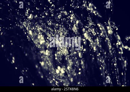 Wassertropfen fliegen in der Luft auf dunklem Hintergrund Stockfoto