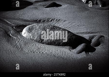 Schwarzweißbild eines großen Steins am Lyme Regis Beach an der Jurassic Coast in Dorset, Großbritannien Stockfoto