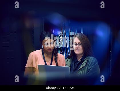 Zwei Technikerinnen, die einen Laptop im Serverraum benutzen Stockfoto