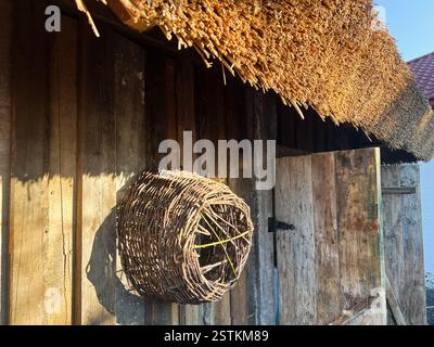 Altes Holzgebäude mit Korbkorb und Strohdach unter Sonnenlicht. Stockfoto