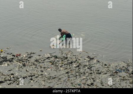 Die Einheimischen waschen ihre Kleidung im Flusswasser, wo sich Plastik- und Müllhaufen auf den Fluss und seine Ufer füllen, was der Meeresökologie und der öffentlichen Gesundheit schadet. Chittagong, Bangladesch. Stockfoto