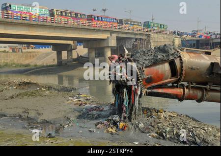 Arbeiter entfernen Kunststoff und andere Ablagerungen aus dem Schleifkopf einer Grabmaschine entlang der verschmutzten Ufer des Karnaphuli River in Chittagong. Müllhaufen haben den Fluss kontaminiert, sich an den Ufern ansammeln und sowohl das Meeresökosystem als auch die menschliche Gesundheit schädigen. Bangladesch. Stockfoto