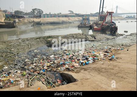 Arbeiter entfernen Kunststoff und andere Ablagerungen aus dem Schleifkopf einer Grabmaschine entlang der verschmutzten Ufer des Karnaphuli River in Chittagong. Müllhaufen haben den Fluss kontaminiert, sich an den Ufern ansammeln und sowohl das Meeresökosystem als auch die menschliche Gesundheit schädigen. Bangladesch. Stockfoto