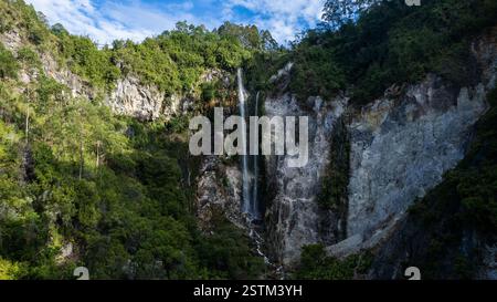 Ein atemberaubender Wasserfall, der sich über felsige Klippen hinunter stürzt, umgeben von üppiger grüner Vegetation. Stockfoto