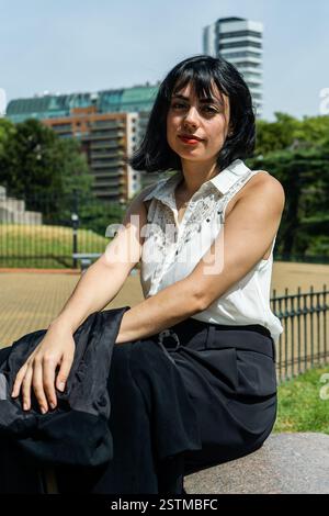 Junge Geschäftsfrau aus lateinamerika, die einen Moment der Ruhe in einem Stadtpark genießt und urbanen Lebensstil und Eleganz präsentiert Stockfoto