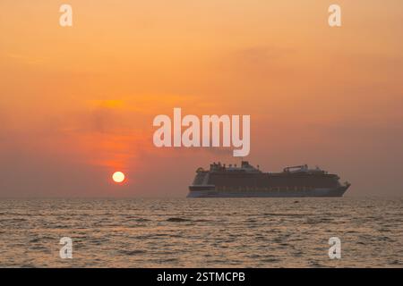 Sonnenuntergang auf einem luxuriösen Kreuzfahrtschiff verwandelt den Himmel orange und rosa und schafft eine atemberaubende Aussicht. Erleben Sie die ruhige Schönheit des Horizonts während des Tagesdurchgangs Stockfoto