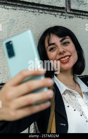 Elegante Geschäftsfrau, die ein Selfie mit ihrem Smartphone in klassischem urbanem Hintergrund macht Stockfoto