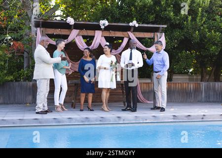Verschiedene Seniorenfreunde feiern am Pool, lächeln und halten Getränke. Feier, Freizeit, Lifestyle, Ruhestand, Genuss, Freundschaft Stockfoto
