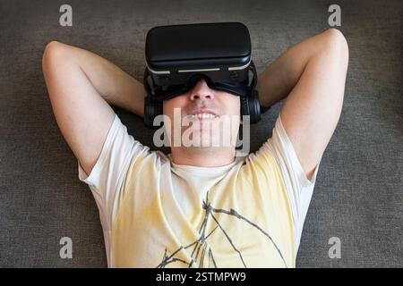 Mensch und Technologie Metaverse Konzept. Porträt eines glücklichen jungen, gutaussehenden Mannes, positiv lächelnder Kerl, der mit modernen Virtual-Reality-Köpfen arbeitet Stockfoto