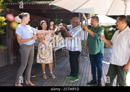 Im Freien locken verschiedene Seniorenfreunde verschiedener Seniorenfreunde mit Champagner für einen fröhlichen Anlass. Feier, ältere Menschen, Freundschaft, Stockfoto