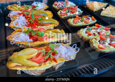 Verschiedene offene Sandwiches mit frischen Belägen in einer Vitrine Stockfoto