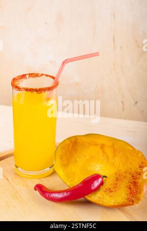 Mangonada mexikanischer Mango-Smoothie mit Chamoy-Sauce und Chilipulver-Gewürz auf hölzernem Hintergrund Stockfoto