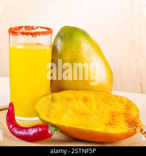 Nahaufnahme des mexikanischen Smoothie-Getränks Mangonada aus Mango und Chilipulver im Glas auf Holztisch Stockfoto