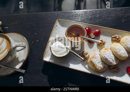 Quark Pfannkuchen mit saurer Sahne, Honig auf dem Tablett. Stockfoto