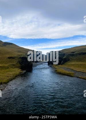 Das Foto zeigt eine atemberaubende natürliche Landschaft mit einem ruhigen Fluss, der durch einen dramatischen Canyon mit zerklüfteten Klippen auf beiden Seiten fließt Stockfoto