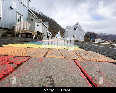 Das Foto zeigt eine bezaubernde Straßenszene in einer kleinen Stadt mit farbenfrohem Bürgersteig und malerischen weißen Häusern vor einer Bergkulisse Stockfoto