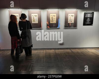 KIEW, UKRAINE - 19. FEBRUAR 2025 - Frauen sehen sich die Bilder des Albums der Uniformen der ukrainischen Armee und Marine für die Zeit des Befreiungskampfes 1917–1921 der ukrainischen Malerin, Heraldistin und Starshyna der ukrainischen Volksrepublik Mykola Bytytnskyi an, das während der Ausstellung „Schild auf dem Schild“ im Nationalmuseum der ukrainischen Geschichte im Zweiten Weltkrieg am Tag des nationalen Emblems der Ukraine, Kiew, gezeigt wurde. Hauptstadt der Ukraine. (Foto: Hennadii Minchenko/Ukrinform) Stockfoto