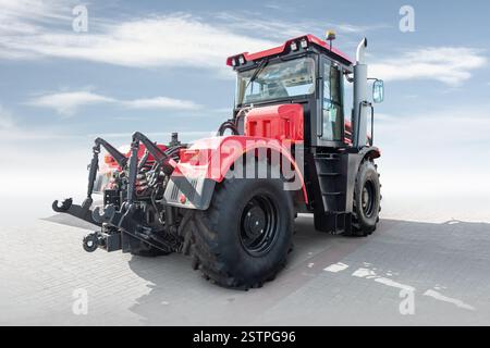 Roter schwerer Radtraktor isoliert auf hellem Hintergrund mit Himmel Stockfoto