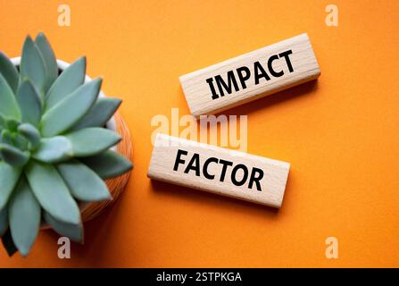 Symbol für Aufprallfaktor. Holzblöcke mit den Worten Impact Factor. Schöner oranger Hintergrund mit saftiger Pflanze. Business and Impact Factor Konzept. Co Stockfoto