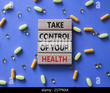 Gesundheitssymbol. Concept Word Nehmen Sie die Kontrolle über Ihre Gesundheit auf Holzblöcken. Schöner lila Hintergrund mit Pillen. Medizinkonzept. Kopierbereich Stockfoto