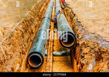 Unterirdische Rohrleitungen werden im Graben befestigt. Der Mensch macht ein kreisförmiges Schweißen Stockfoto