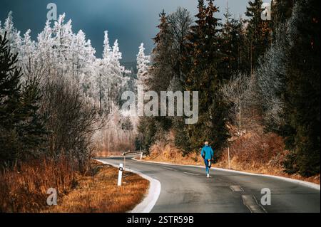 Ein Läufer, der während des Wintertrainings in einer abgelegenen Landschaft durch eisige Hügel fährt. Stockfoto