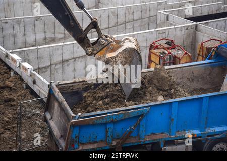Bagger Graben und Entladen von Schmutz auf der Baustelle in den Muldenkipper Stockfoto