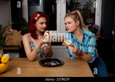 Zwei Freunde genießen gemeinsam Pizza in einer gemütlichen und einladenden Küche Stockfoto