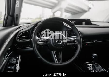 Fahren Sie mit Mazda CX-30 in einer Stadt. Blick vom Fahrersitz auf ein modernes Auto, während Sie unter der Brücke parken. Stockfoto