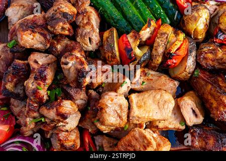 Köstliche Spieße mit gegrilltem Fleisch und lebendigem Gemüse werden auf einer Holzplatte präsentiert. Dieses farbenfrohe Display zeigt appetitliche Texturen und Stockfoto