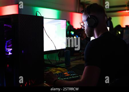 Spieler, der an einem Spielwettbewerb teilnimmt, vor einem Computermonitor sitzt und Videospiele spielt. Stockfoto
