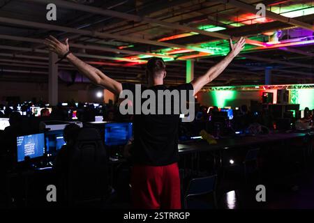 Junger Mann, ein Gamer beim digitalen Festival, der im Computerraum steht. Gaming-Lifestyle und Community-Konzepte. Stockfoto