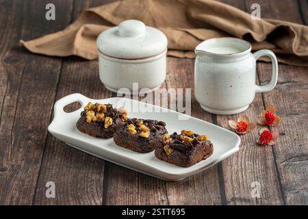 Schokoladen-Walnuss-Brownies auf weißer Platte mit Milchkrug Stockfoto