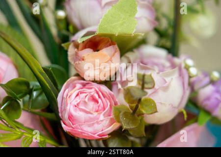 Ein wunderschönes Blumenarrangement zeigt Rosen und Grün in zarten Rosa- und Lavendeltönen. Perfekt zum Aufhellen eines Raumes, bringt es einen an Stockfoto