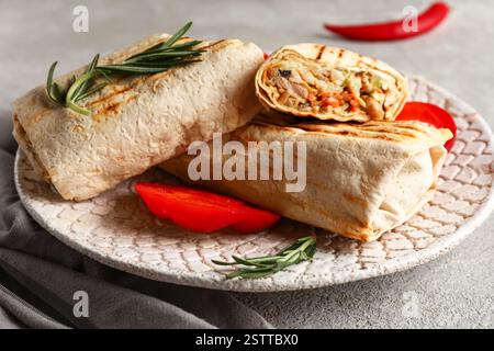 Teller mit leckerem Schawarma und Scheiben Paprika auf grauem Tisch Stockfoto