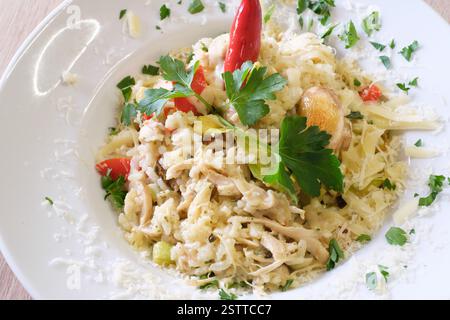 Cremiges Risotto mit Hühnchen und Pilzen garniert mit frischer Petersilie und Chili Stockfoto