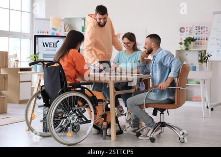 Team von Designern, die mit Kollegen im Rollstuhl im Büro arbeiten Stockfoto