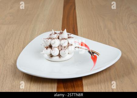 Elegantes Dessert mit Meringue und Schokoladenmousse mit Kakaopulver auf einem weißen Teller Stockfoto