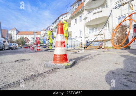 Orangefarbener und weißer Verkehrskegel auf einer Baustelle in der Stadt, Wend Glasfasermontage während der Installation von Kabelkanälen für Glasfaserkabel, ME Stockfoto