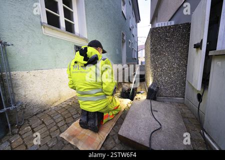 Arbeiter in gut sichtbarer Kleidung kniend auf Kopfsteinpflaster während der Bauarbeiten neben Gebäuden, Wend Glasfasermontage während der Installation Stockfoto