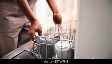Reinigung, Hände und Laden Geschirrspüler zu Hause mit Tassen für den Reinigungsservice, Hausarbeit und Technologie. Hausarbeiten, Küche und Person mit Geschirr Stockfoto