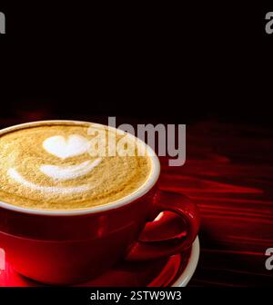 Rote Tasse Kaffee mit aufgeschäumter Milch und Latte Art mit Copyspace oben Stockfoto