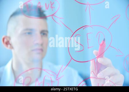 Manager schreibt SEO-Diagramm auf transparentem Bildschirm. Webtechnologie und Suchmarketing-Konzept. Nahaufnahme Stockfoto
