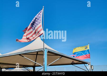 Amerikanische und venezolanische Fahnen winken Seite an Seite vor einem klaren blauen Himmel und symbolisieren Einheit und internationale Beziehungen. Perfekt für Diplo-Themen Stockfoto