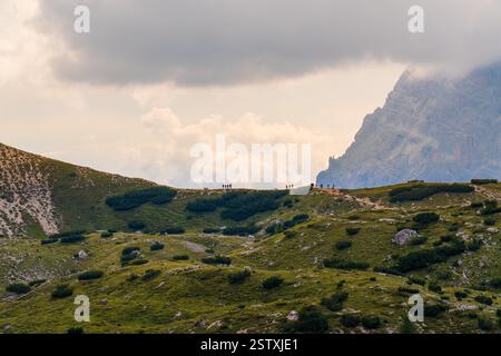 Gruppenwanderer begeben sich auf den malerischen Bergpfad in den Dolomiten, umgeben von atemberaubender alpiner Landschaft. Eine abenteuerliche Reise durch rugg Stockfoto