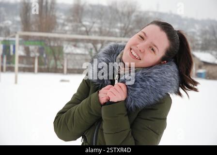 Fröhlicher Wintertag mit lächelnder Frau in warmer Kleidung draußen. Stockfoto