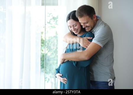 Asiatische schwangere Frau und Mann, die zu Hause den Bauch betrachten Stockfoto