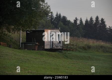 Modulhaus auf Rädern mit Außensauna und Sprudelbad oder Whirlpool auf der Natur mit Berghügel Hintergrund im Wald. Entspannte Atmosphäre Stockfoto