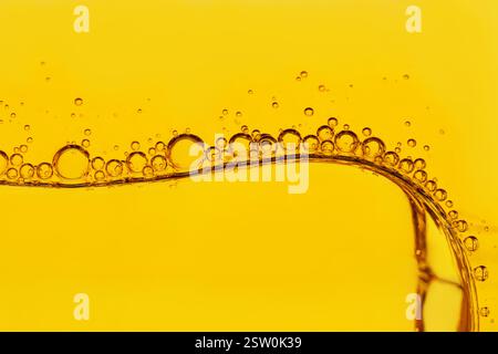 Makroaufnahme einer hinterleuchteten Wasser-Öl-Emulsion über farbigem Hintergrund. Gas-Flüssig-Öl. Mehrphasiges Gemisch. Winzige Gasblasen in einer größeren Ölblase Stockfoto